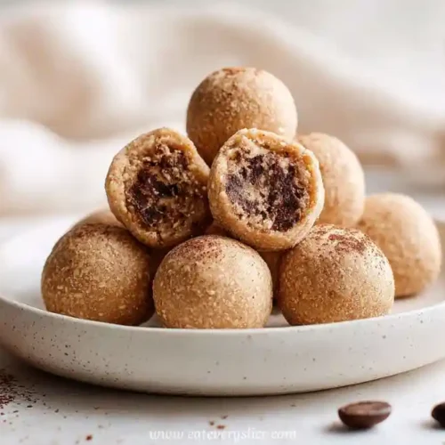 no-bake espresso almond tiramisu energy bites stacked on a white plate, dusted with cocoa powder