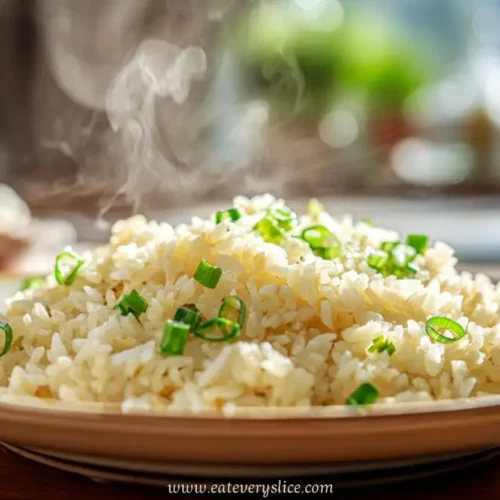 Steaming garlic fried rice topped with chopped scallions on a plate