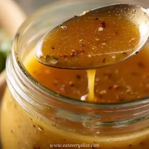Spoonful of healthy Italian dressing above a mason jar with herbs and chili flakes