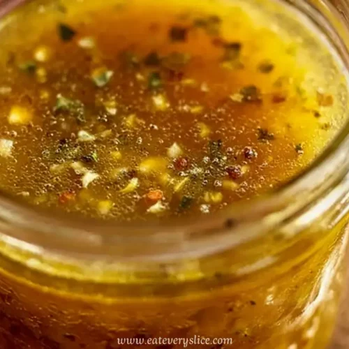 Homemade Italian dressing in a mason jar with herbs and garlic visible