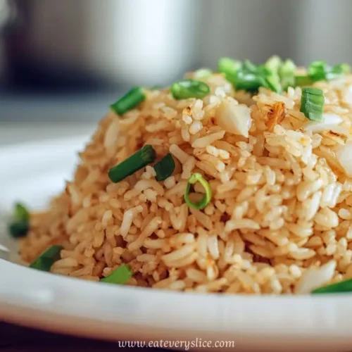Dome of garlic fried rice garnished with chopped green onions on a white plate