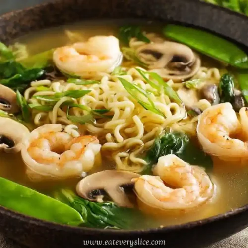Bowl of shrimp ramen with mushrooms, snow peas, scallions, and spinach in a light broth.