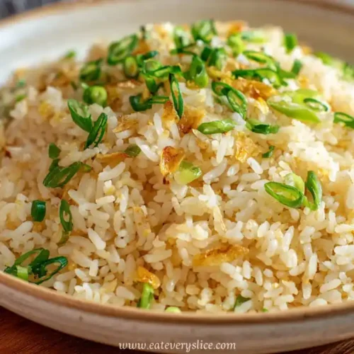 Bowl of simple garlic fried rice with chopped scallions on a wooden board