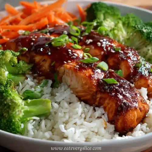 spicy honey garlic glazed salmon over white rice with broccoli and carrots in a bowl