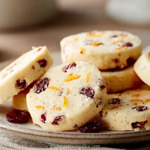 Cranberry orange shortbread cookies stacked on ceramic plate with dried fruit pieces