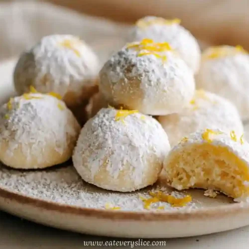 soft powdered lemon cookies on rustic ceramic plate with zest garnish