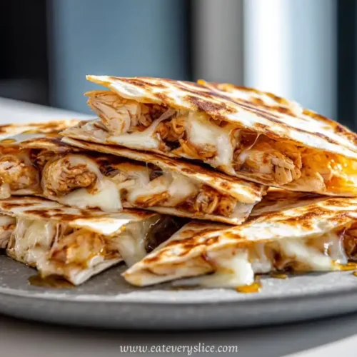 Stack of grilled hot honey chicken quesadilla slices with melted cheese on a gray plate