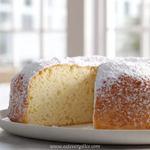 Soft Italian sponge cake dusted with powdered sugar on a white plate near a sunlit window
