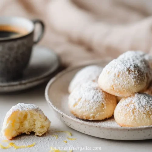 Soft Italian lemon cookies dusted with powdered sugar beside a rustic espresso cup