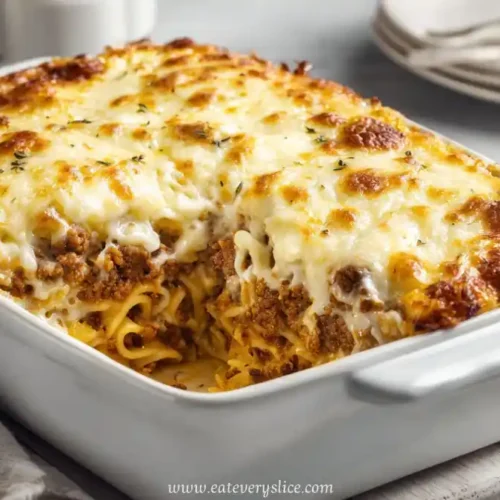 Sliced Italian-style meatloaf casserole with cheesy pasta layers in a white baking dish