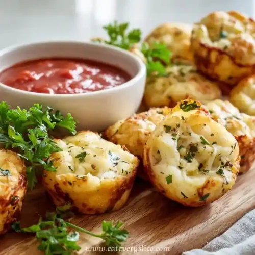 Mini Italian cheese and herb bites on wooden board with marinara dipping sauce and parsley