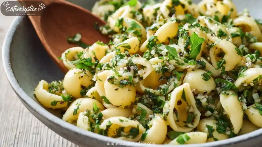 Shell pasta salad with fresh herbs, garlic, and olive oil in a ceramic bowl