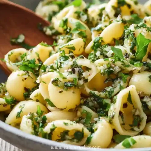 Shell pasta salad with fresh herbs, garlic, and olive oil in a ceramic bowl
