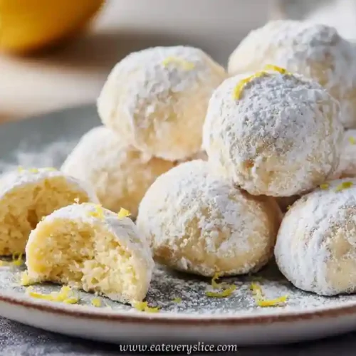 soft lemon powdered sugar cookies on ceramic plate with zest garnish