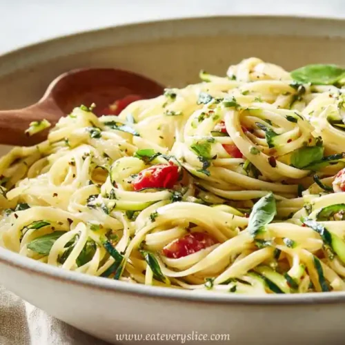 summer pasta salad with linguine, zucchini ribbons, cherry tomatoes, and fresh basil in ceramic bowl