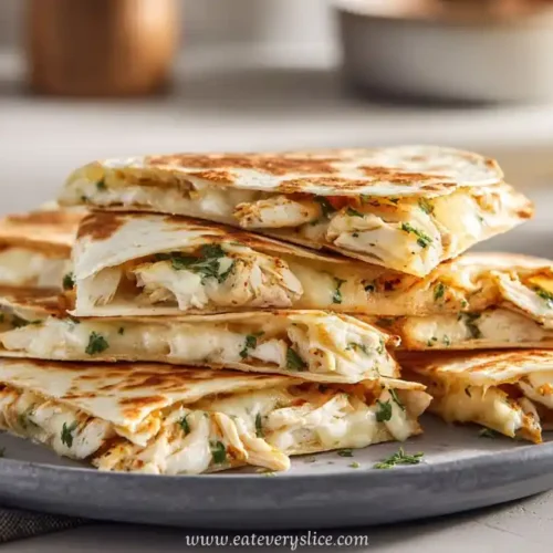 grilled chicken quesadilla wedges stacked on grey plate with fresh herbs