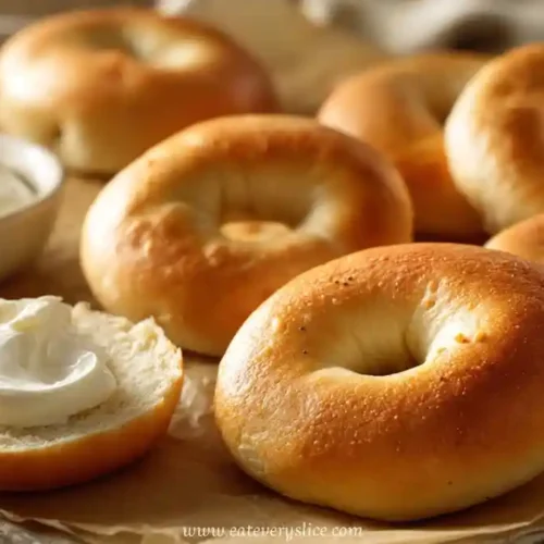 freshly baked plain Greek yogurt bagels served with cream cheese on parchment paper