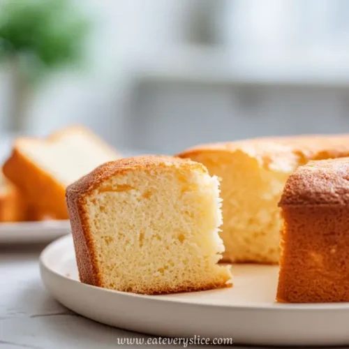 golden slice of soft yeasted sponge cake on white plate with blurred background