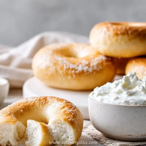 Soft golden yogurt bagels served with whipped cream cheese and flour on a neutral breakfast setup