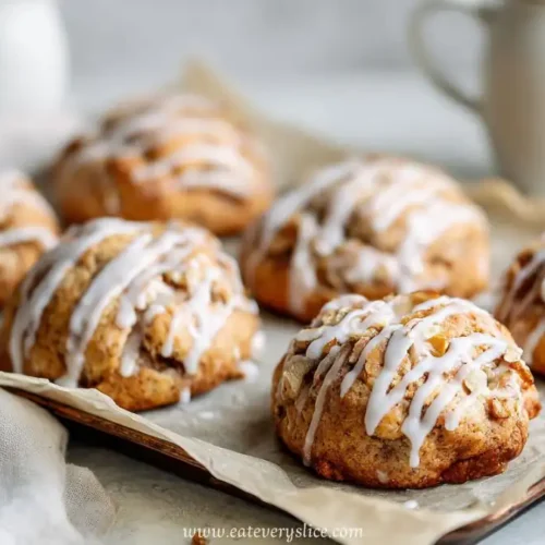 golden apple fritters with vanilla glaze on baking tray with coffee cups