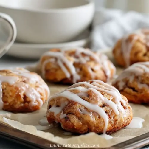 Soft baked apple fritters with vanilla glaze on a baking tray beside a coffee cup