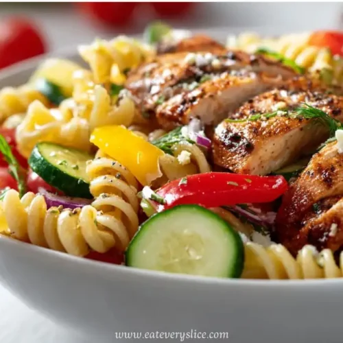 Grilled chicken pasta salad with rotini, zucchini, cherry tomatoes, bell peppers, and herbs in a white bowl
