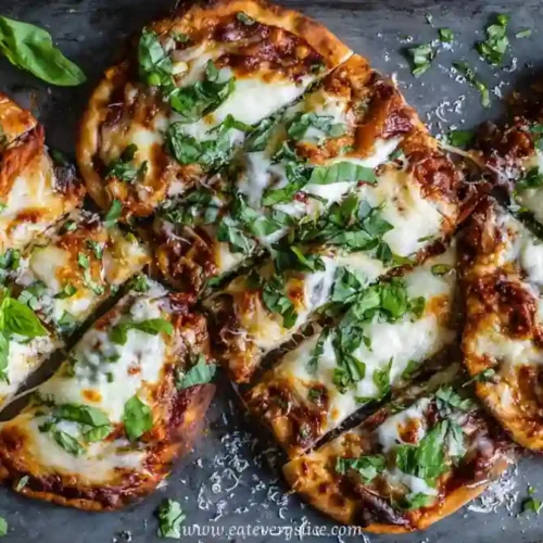 mini pizzas topped with melted mozzarella tomato sauce and fresh basil on baking tray